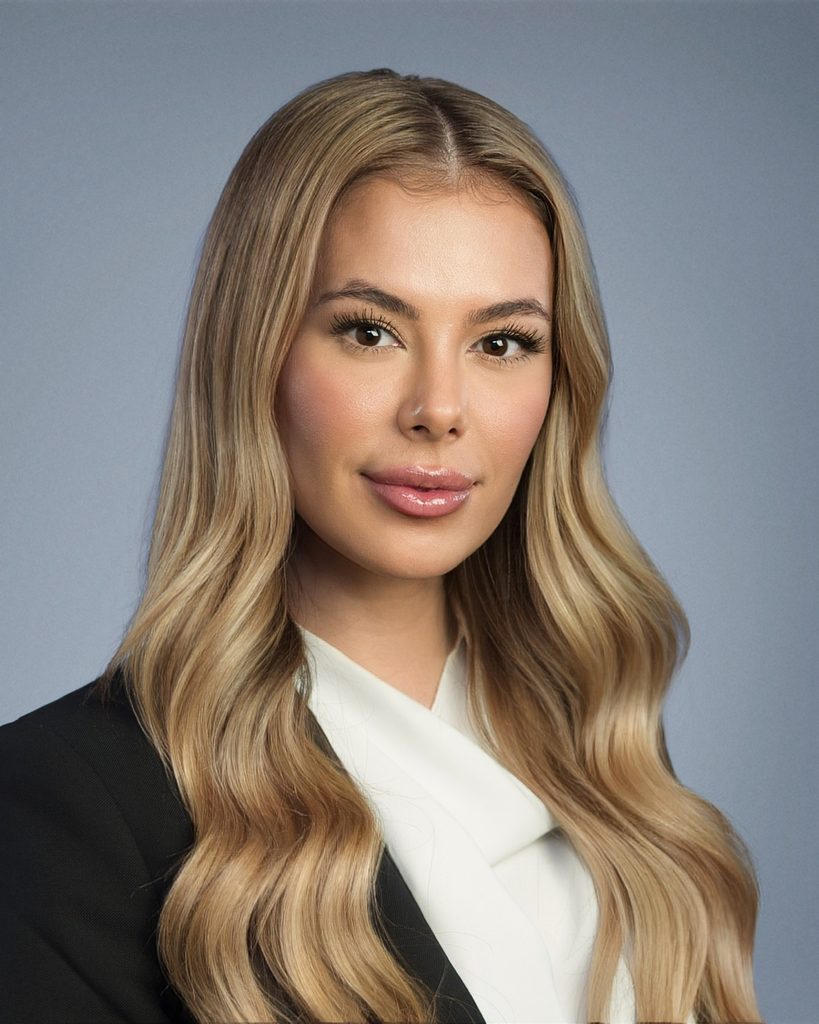 Tessa Reisner, PMP, Distinguished Cheetah Alum award winner sits for a professional headshot with blonde wavy hair, a slight smile, wearing a black blazer over a white top.
